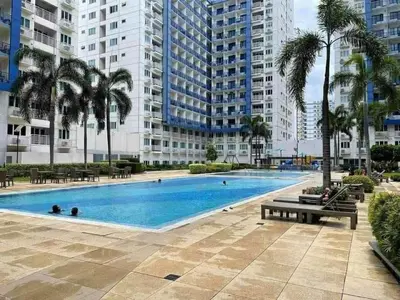 a large swimming pool with palm trees and buildings at 1Br Sea Residences affordable staycatiom in Manila