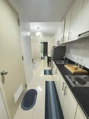 a kitchen with white cabinets and black counter tops at 1Br Sea Residences affordable staycatiom in Manila