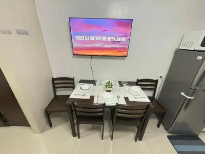 a dining room with a table with chairs and a television at 1Br Sea Residences affordable staycatiom in Manila