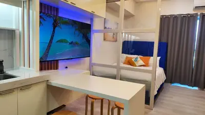 a kitchen with a table and a bedroom with a bed at Grace Residences Taguig in Manila