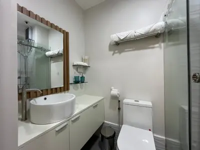 a white bathroom with a sink and a toilet at Grace Residences Taguig in Manila