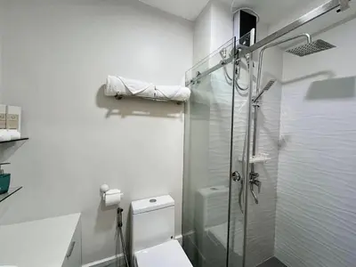a white bathroom with a shower and a toilet at Grace Residences Taguig in Manila