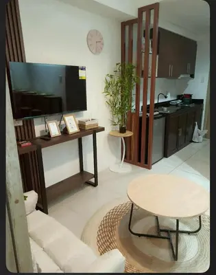 a living room with a large television and a table at Boho Cove PH in Manila