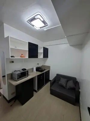 a room with a kitchen with a microwave and a couch at Pod 520 in Manila