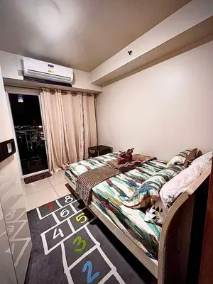 a bedroom with a bed with a cat laying on it at MOA Staycation Condotel in Manila
