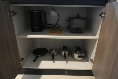 a cupboard with a coffee maker and pots and pans at Bruné - Parañaque in Manila