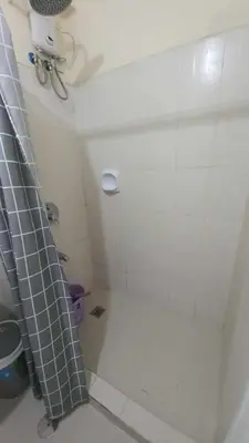 a bathroom with a shower with a white tiled wall at La Verti Residences 1524 in Manila