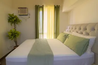 a bedroom with a white bed with two green pillows at La Verti Residences 1524 in Manila