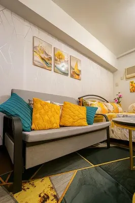 a couch with yellow pillows in a room with a bed at La Verti Residences 1520 in Manila