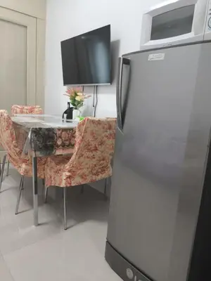 a kitchen with a refrigerator and a table with a tv at Sea Residence-Rosa in Manila