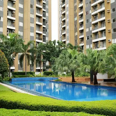 a large blue swimming pool with palm trees and buildings at The Hive Cozy 1-BR Retreat in Taytay