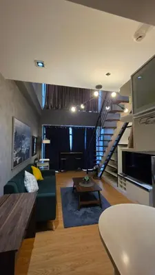 a living room with a green couch and a staircase at Urban Retreat at The Gramercy Residences Makati in Manila