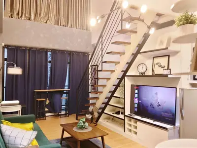 a living room with a staircase and a tv at Urban Retreat at The Gramercy Residences Makati in Manila