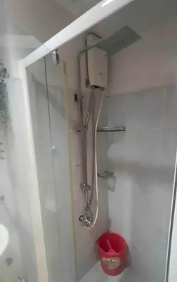 a bathroom with a shower and a red trash can at cozy room at Sea Res in Manila