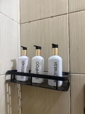 a shelf with four shampoo bottles on a wall at TGG Suites at Birch Tower in Manila