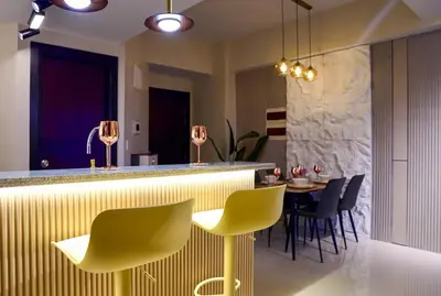 a kitchen with a bar with yellow chairs and a table at Luxury 2BR in Uptown Parksuites BGC Balcony & Prime location in Manila