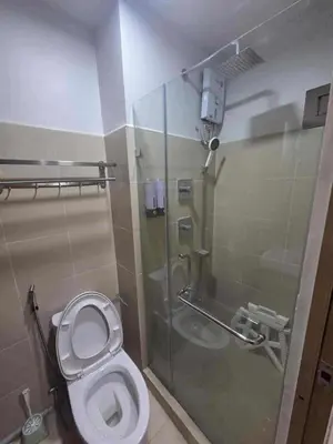 a bathroom with a toilet and a glass shower at City Escape Haven in Manila