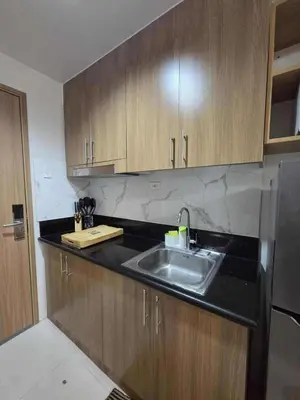 a kitchen with a sink and wooden cabinets at City Escape Haven in Manila