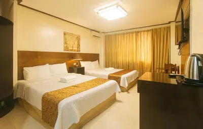 a hotel room with two beds and a television at The Shilla Philia Hotel by RedDoorz in Manila