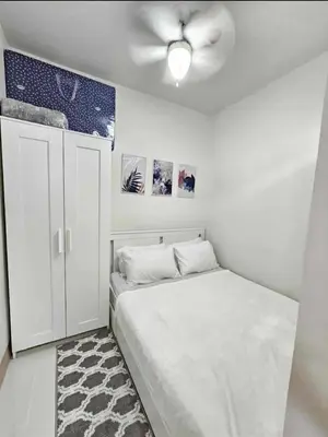 a white bedroom with a bed and a ceiling fan at New Crib at Shore 3 in Manila