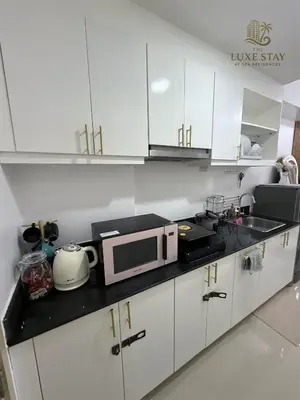 a kitchen with white cabinets and a microwave at The Luxe Stay at Sea Residences in Manila