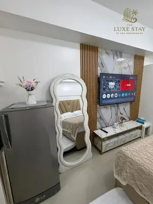 a room with a mirror and a tv and two beds at The Luxe Stay at Sea Residences in Manila