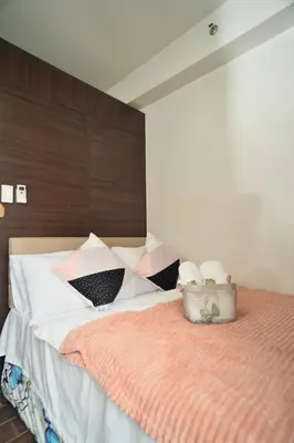 a bedroom with a bed with an orange blanket at The Dream Scape SMDC Air Residences Makati in Manila