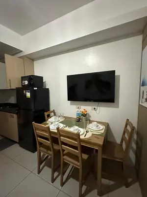 a kitchen with a table with chairs and a television at Sweet Villa SMDC Breeze Residences Pasay in Manila