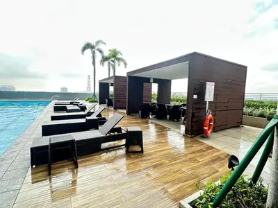 a row of couches and chairs on a swimming pool at Sunset heights SMDC Breeze Residences Pasay in Manila