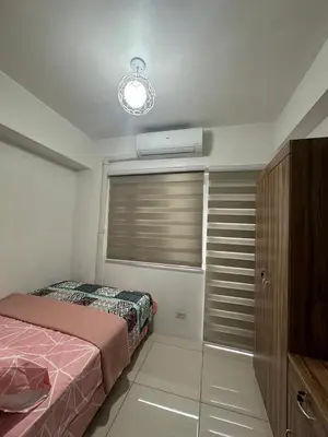a bedroom with a bed and a window with a air conditioner at Sunset heights SMDC Breeze Residences Pasay in Manila