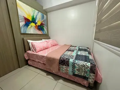 a small bedroom with a bed with a painting on the wall at Sunset heights SMDC Breeze Residences Pasay in Manila