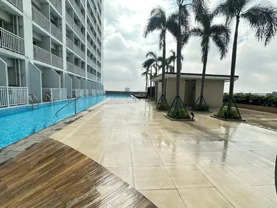 a swimming pool in the middle of a building with palm trees at Sunset heights SMDC Breeze Residences Pasay in Manila