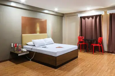 a bedroom with a bed and two red chairs at Hotel Sogo Baclaran in Manila