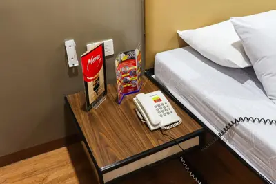 a bed with a table with a phone on it at Hotel Sogo Baclaran in Manila