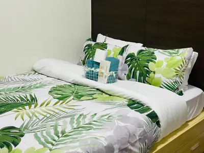 a bed with green and white blankets and pillows at City View Skyline - Air Residence in Manila