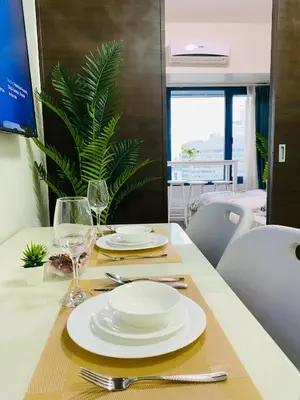 a dining table with white plates and glasses on it at City View Skyline - Air Residence in Manila