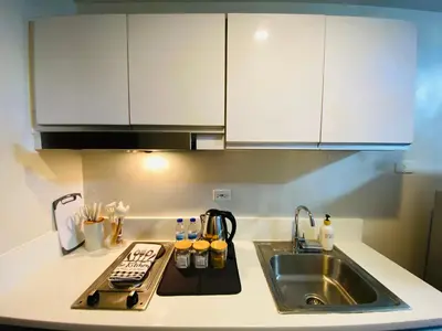 a kitchen with white cabinets and a sink at City View Skyline - Air Residence in Manila