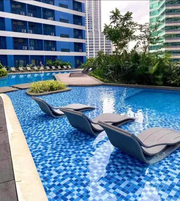 a swimming pool with chaise lounge chairs in a building at City View Skyline - Air Residence in Manila