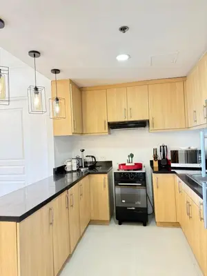 a kitchen with wooden cabinets and black counter tops at Avant BGC 2 Bedroom in Manila