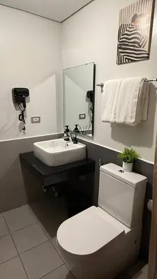 a bathroom with a white toilet and a sink at Casa Forma in Manila