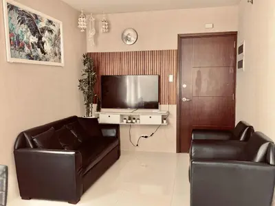 a living room with two leather chairs and a flat screen tv at Serene Suites Condo unit in Bacoor