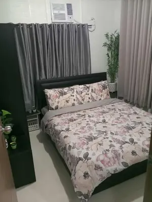 a bedroom with a bed with a floral comforter at Serene Suites Condo unit in Bacoor