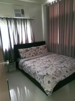 a bed in a bedroom with pink curtains at Serene Suites Condo unit in Bacoor