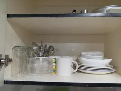 a shelf with plates and cups and dishes on it at Serene Suites Condo unit in Bacoor