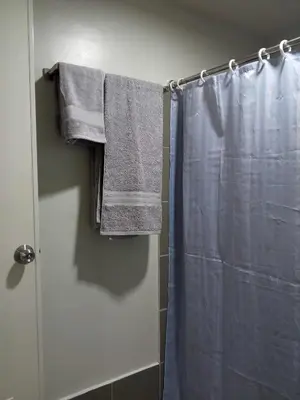 a bathroom with a shower with a blue shower curtain at Serene Suites Condo unit in Bacoor