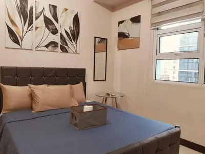 a bedroom with a bed with a blue blanket and a window at #Affordable Condotel Newport Boulevard in Manila