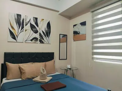 a bedroom with a blue bed with paintings on the wall at #Affordable Condotel Newport Boulevard in Manila