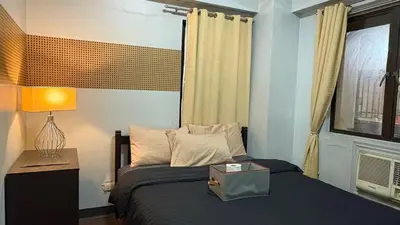 a bedroom with a bed with a lamp and a window at Super Cozy Apartment-Newport Boulevard in Manila