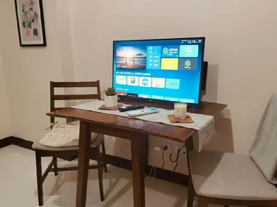 a computer monitor on a wooden table with two chairs at Super Cozy Apartment-Newport Boulevard in Manila