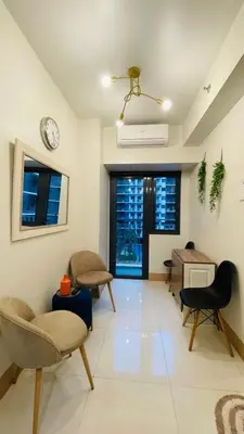 a living room with chairs and a clock on the wall at Lana Haven in Manila